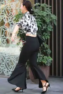 街拍时尚的美女穿印花衬衣搭配黑色喇叭裤出街,霸气侧漏