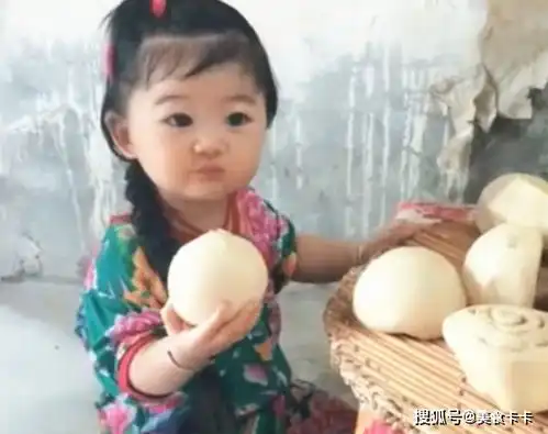 小姑娘坐在板凳上吃大包子,穿着漂亮的花衣服,大眼睛十分的可爱
